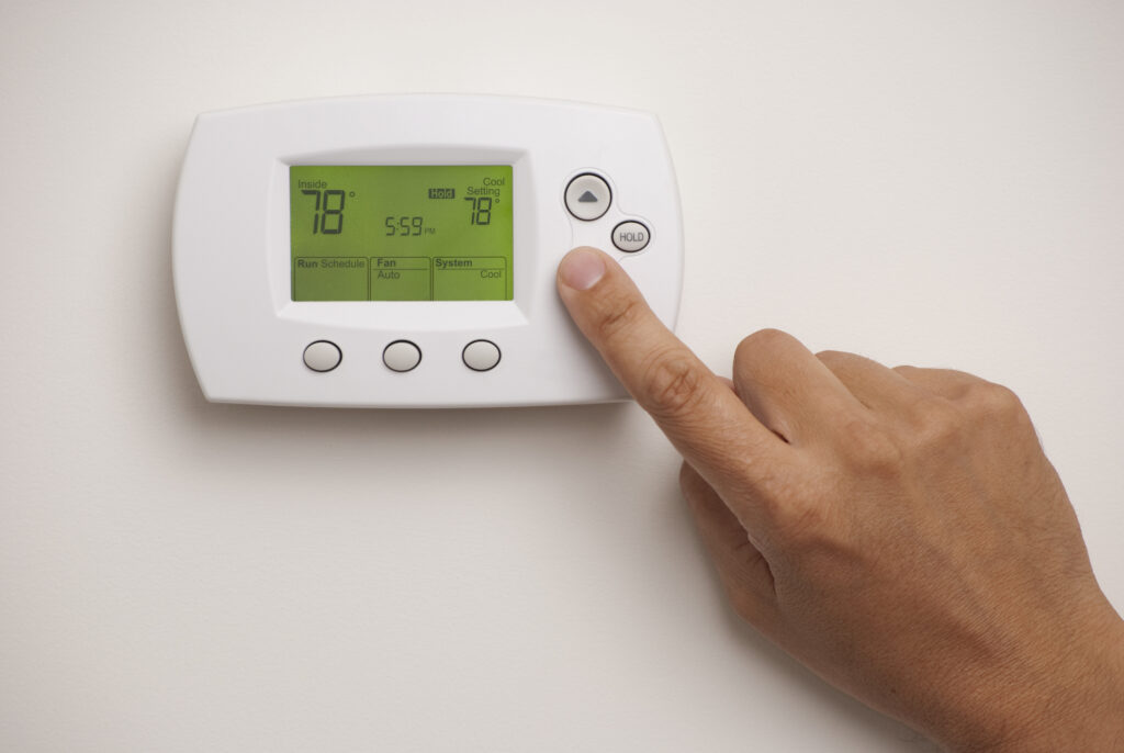Homeowner adjusting digital thermostat to 78 degrees