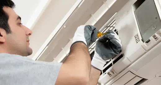 Technician working on a ductless HVAC unit inside
